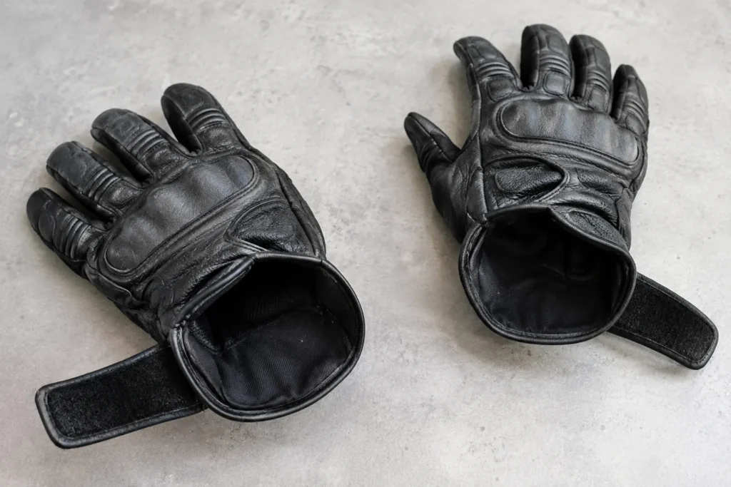Deux gants moto posés séparément, poignets ouverts et doublures visibles.