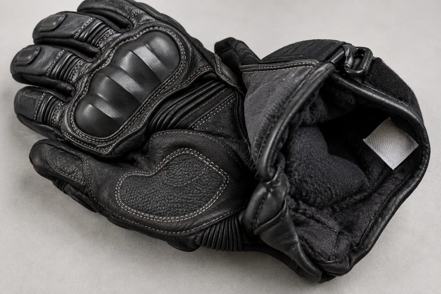 Détail d’un gant chauffant montrant la coque des phalanges, le renfort de paume et son étiquette intérieure.