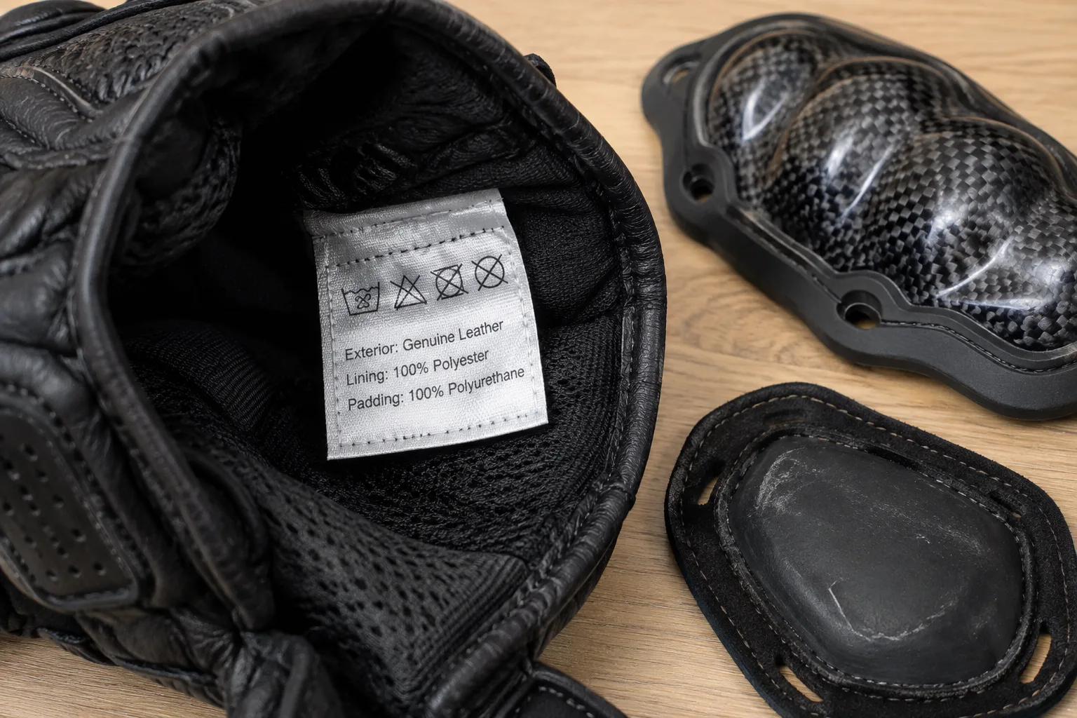 Étiquette de conformité à l’intérieur d’un gant de moto, à côté d’une coque et d’un slider de paume.