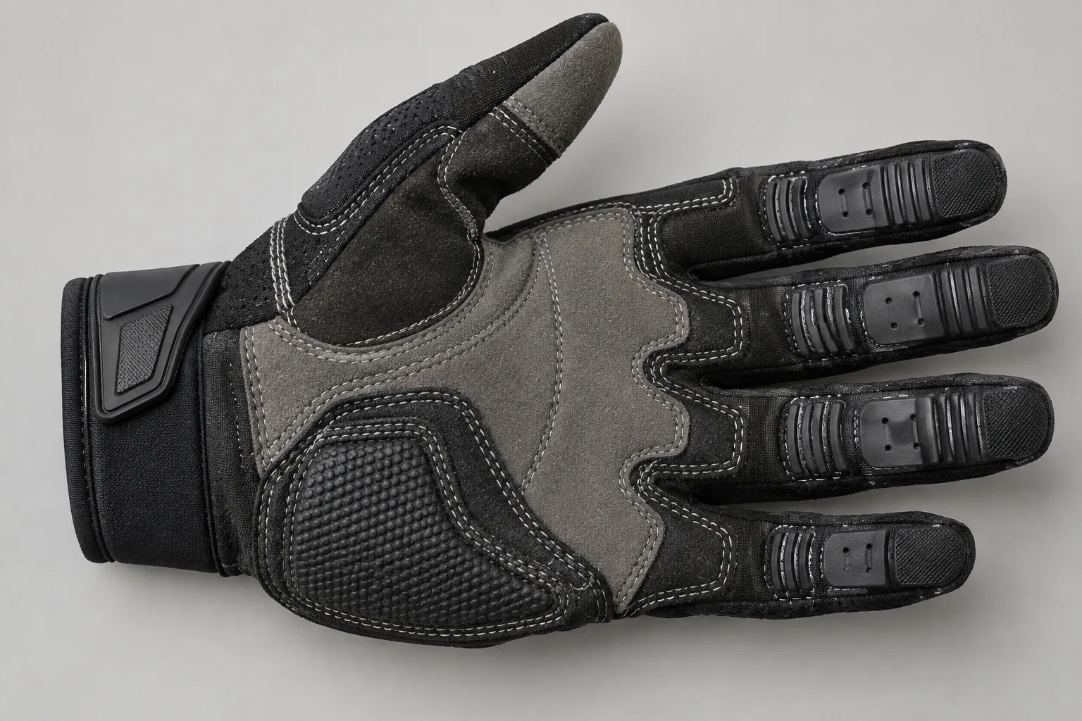 Gant de motocross retourné montrant les coutures de la paume et les panneaux renforcés des doigts.