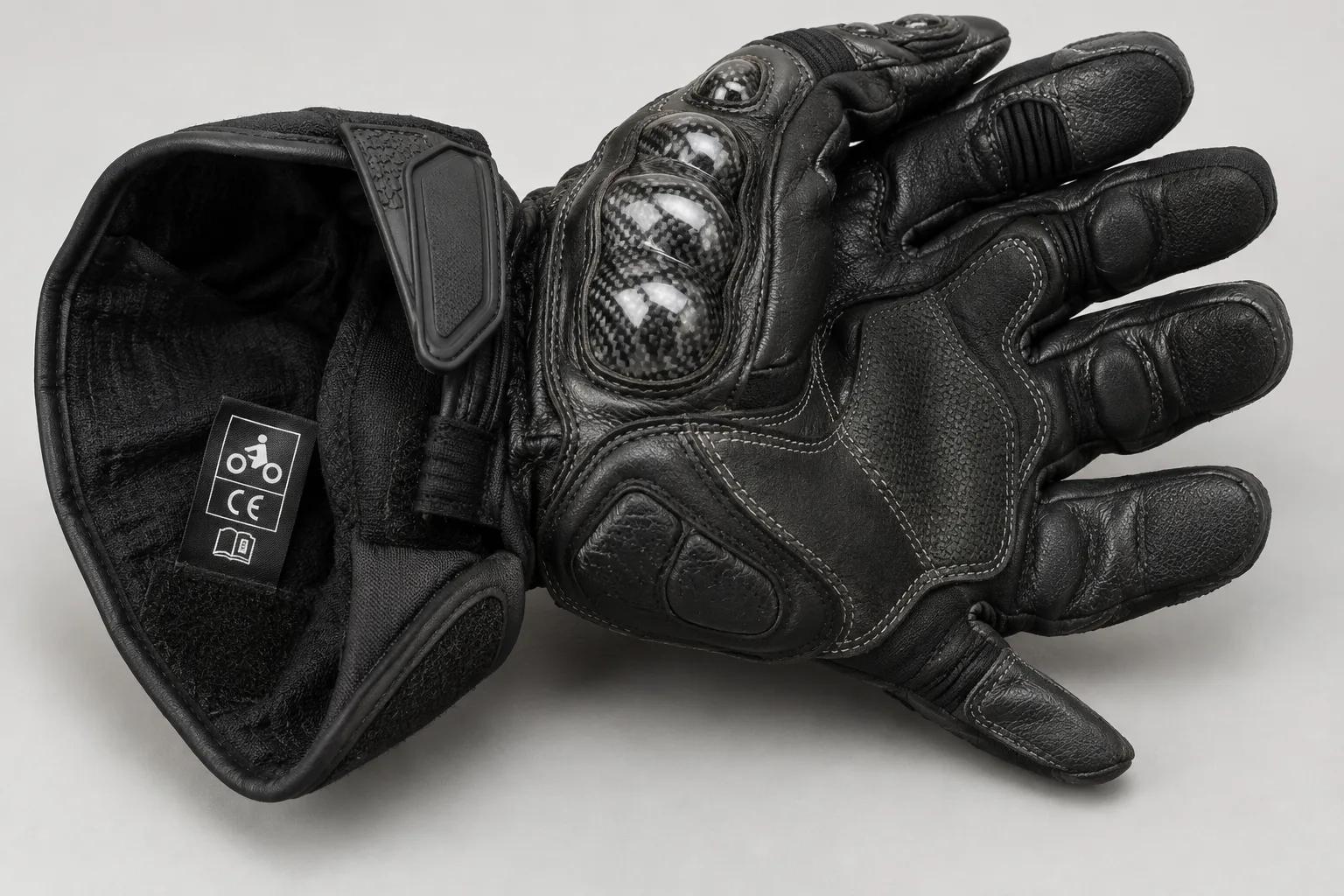 Gant de moto présentant une paume renforcée, une coque sur les phalanges et une étiquette intérieure.