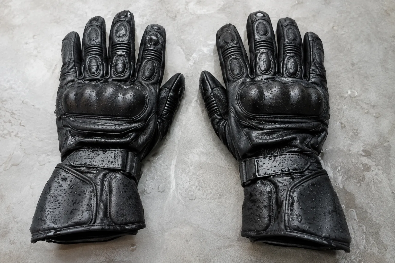 Deux gants de moto sont posés à plat, les doigts déployés, sur une surface propre.