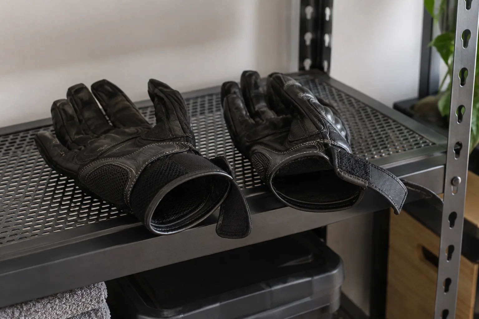 Gants de moto ouverts sur une étagère, avec leurs coutures et leurs fermetures au poignet visibles.